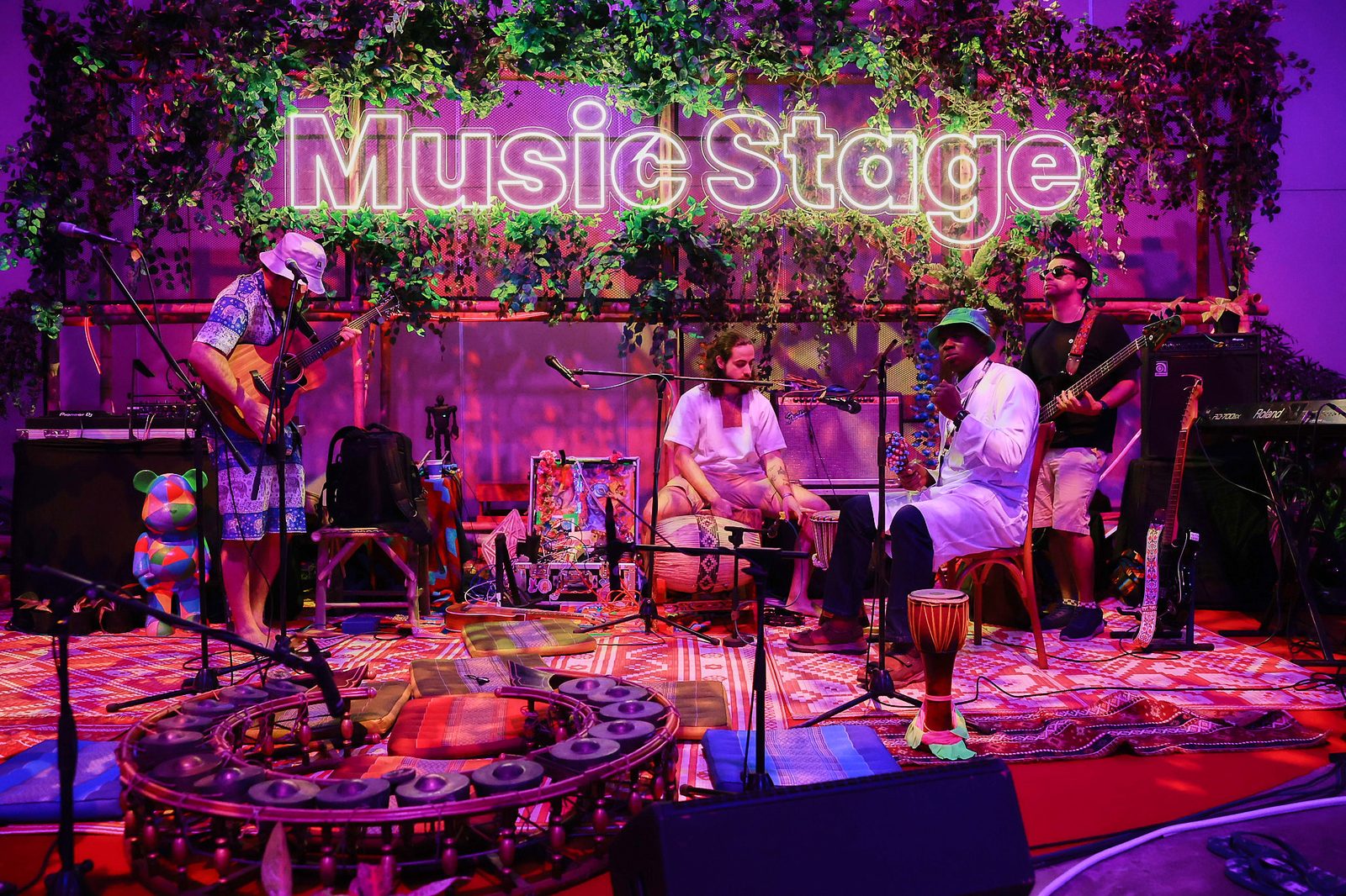 The Music Stage at Devcon SEA β neon sign, jungle leaves, musicians and instruments in a circle